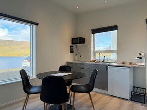 Cozinha moderna com vista para um lago, área de jantar com cadeiras pretas e uma máquina de lavar louça branca.