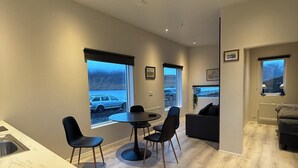 Een moderne woonkamer met een eetgedeelte, grote ramen en uitzicht op een besneeerd landschap.