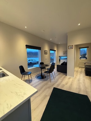 A modern living room with a dining area, large windows, and a view of a snowy landscape.