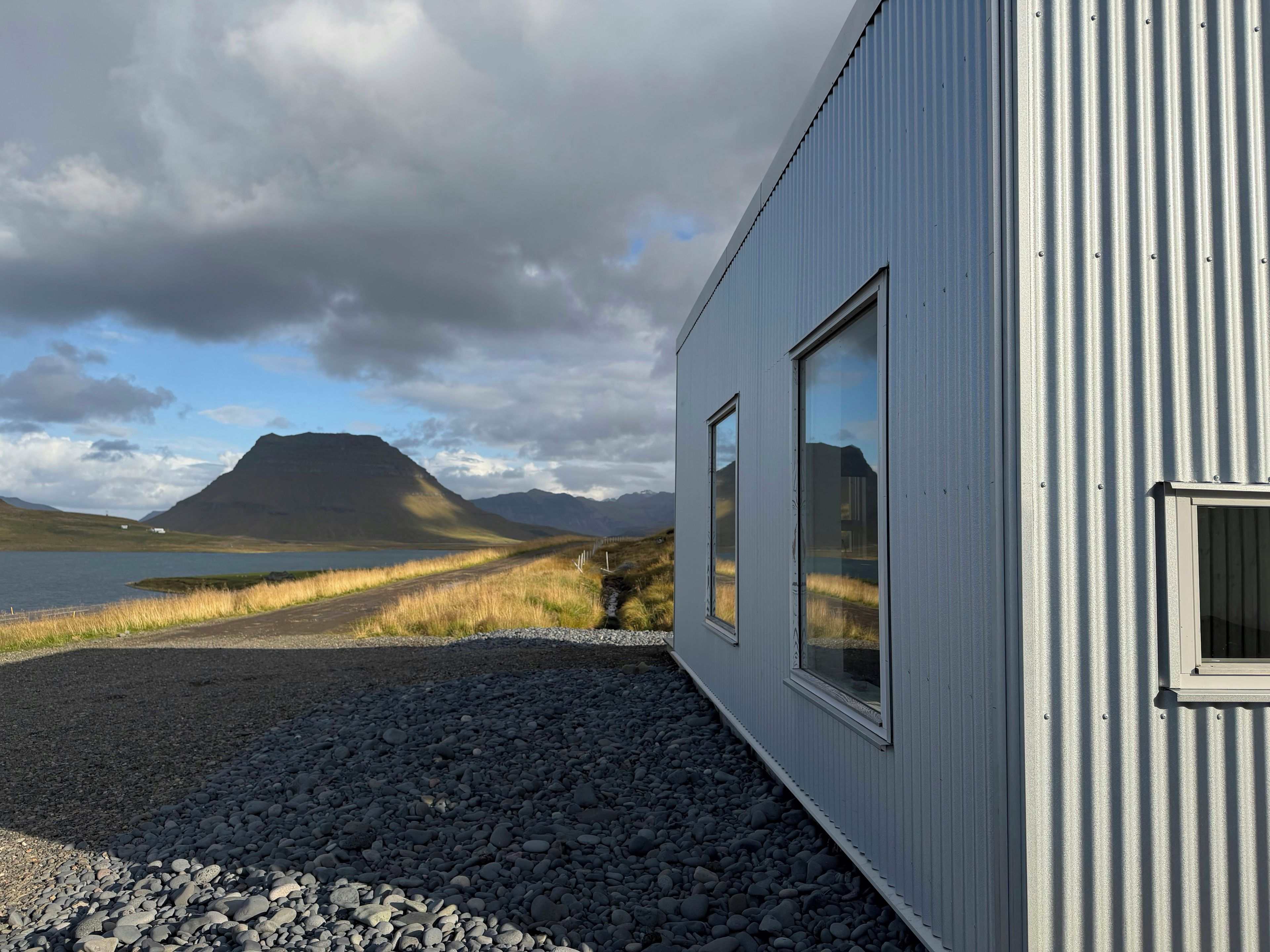 A building with a corrugated metal exterior and a gravel driveway leading to a road.
