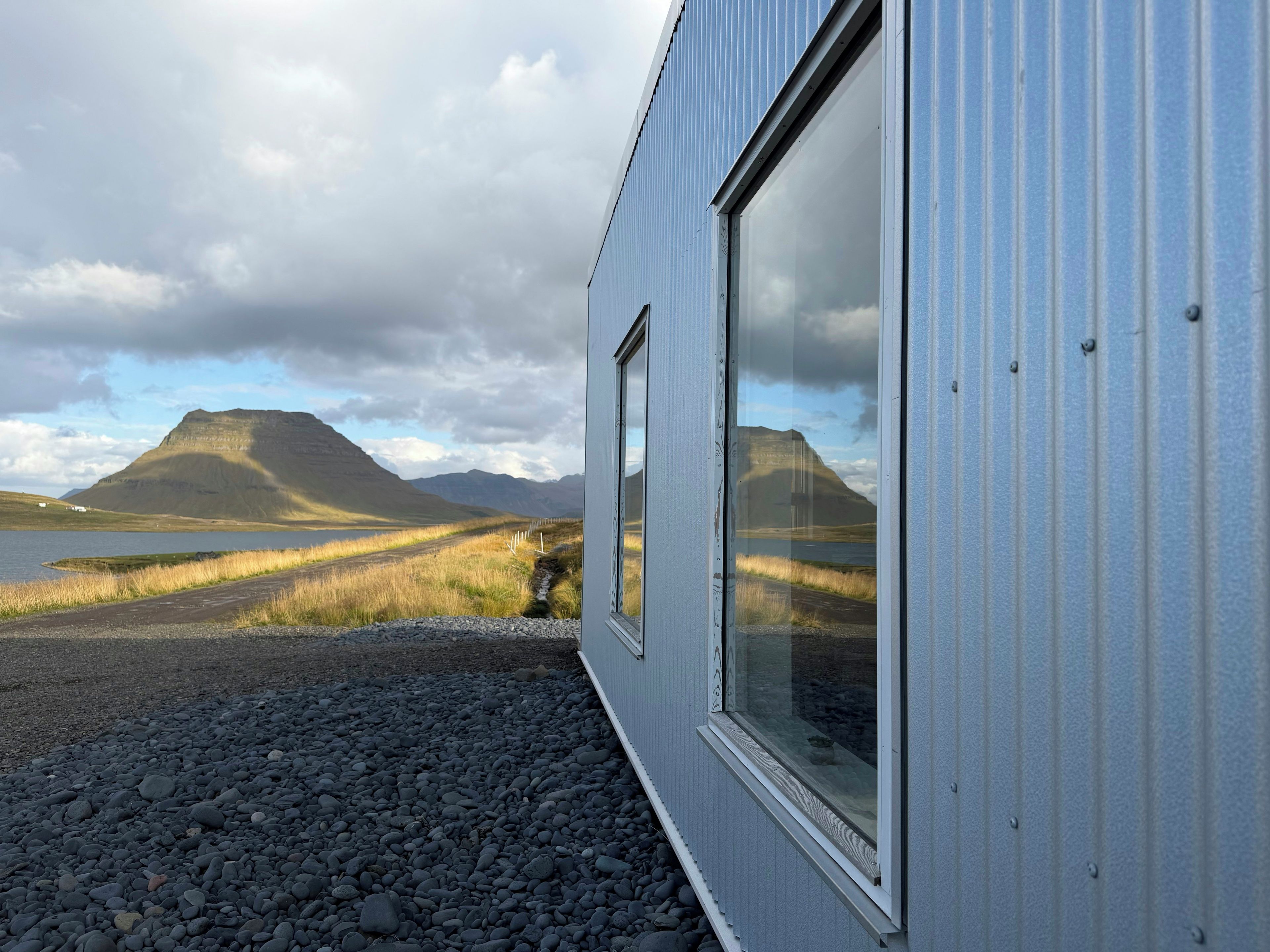 Un edificio con amplios ventanales que dan a un paisaje montañoso y un cuerpo de agua.