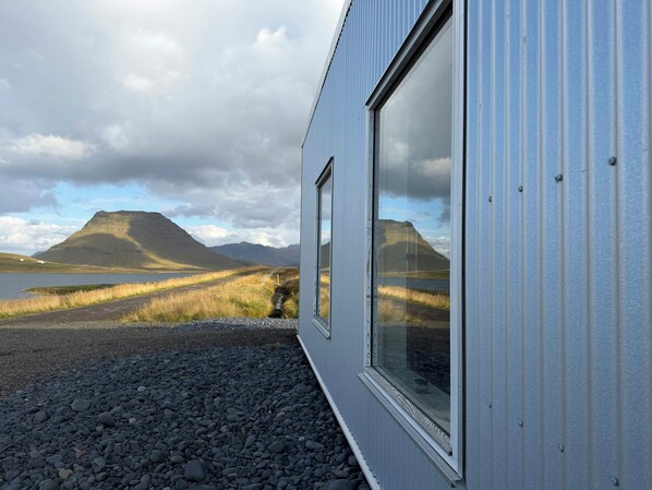Un bâtiment doté de grandes fenêtres donnant sur un paysage montagneux et un plan d’eau.