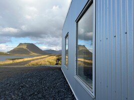 Un edificio con amplios ventanales que dan a un paisaje montañoso y un cuerpo de agua.
