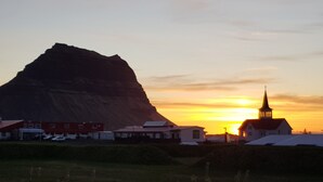 A church with a steeple and a mountain in the background.