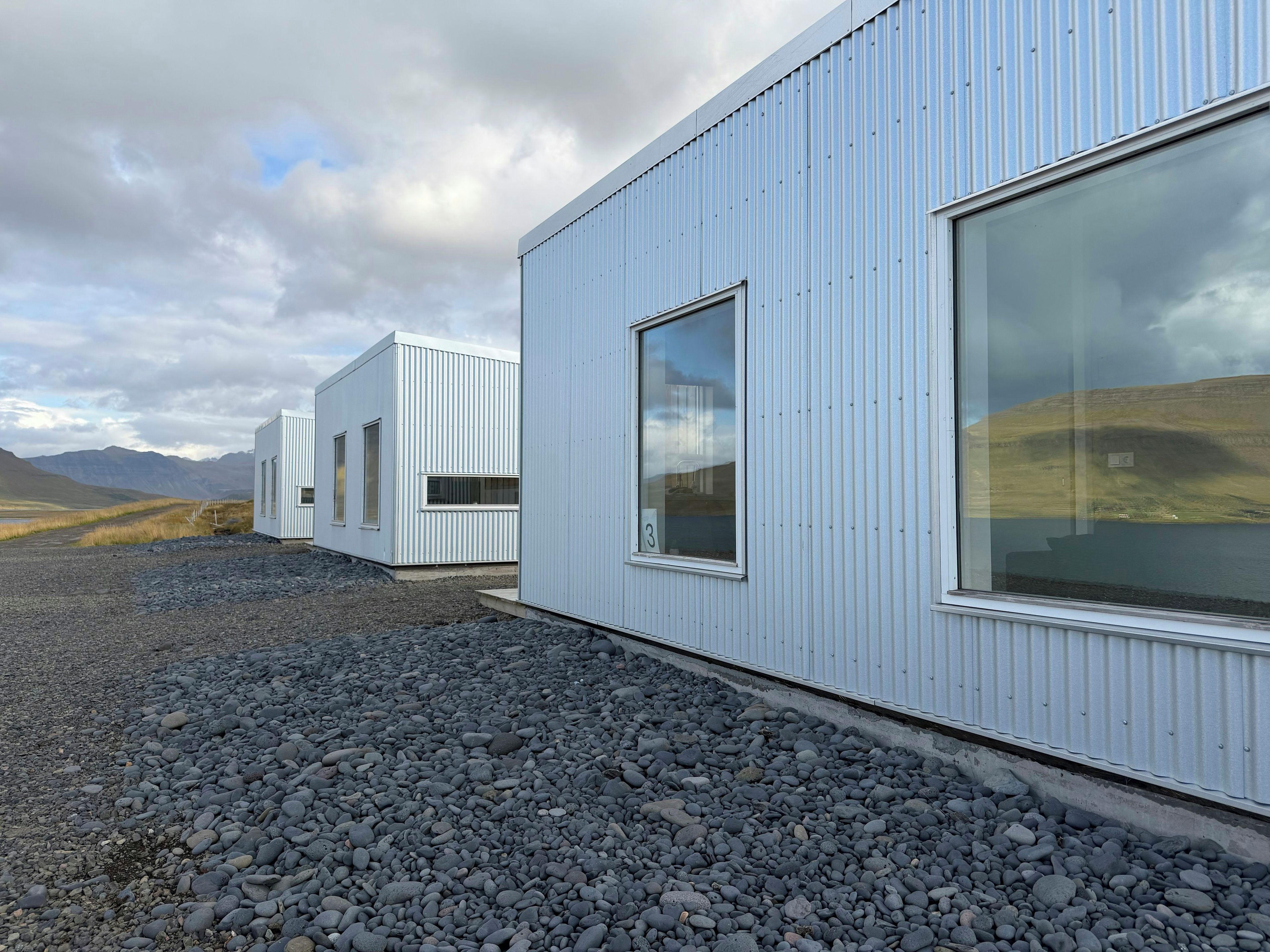 Un bâtiment moderne doté de grandes fenêtres et dont le sol est recouvert de gravier.