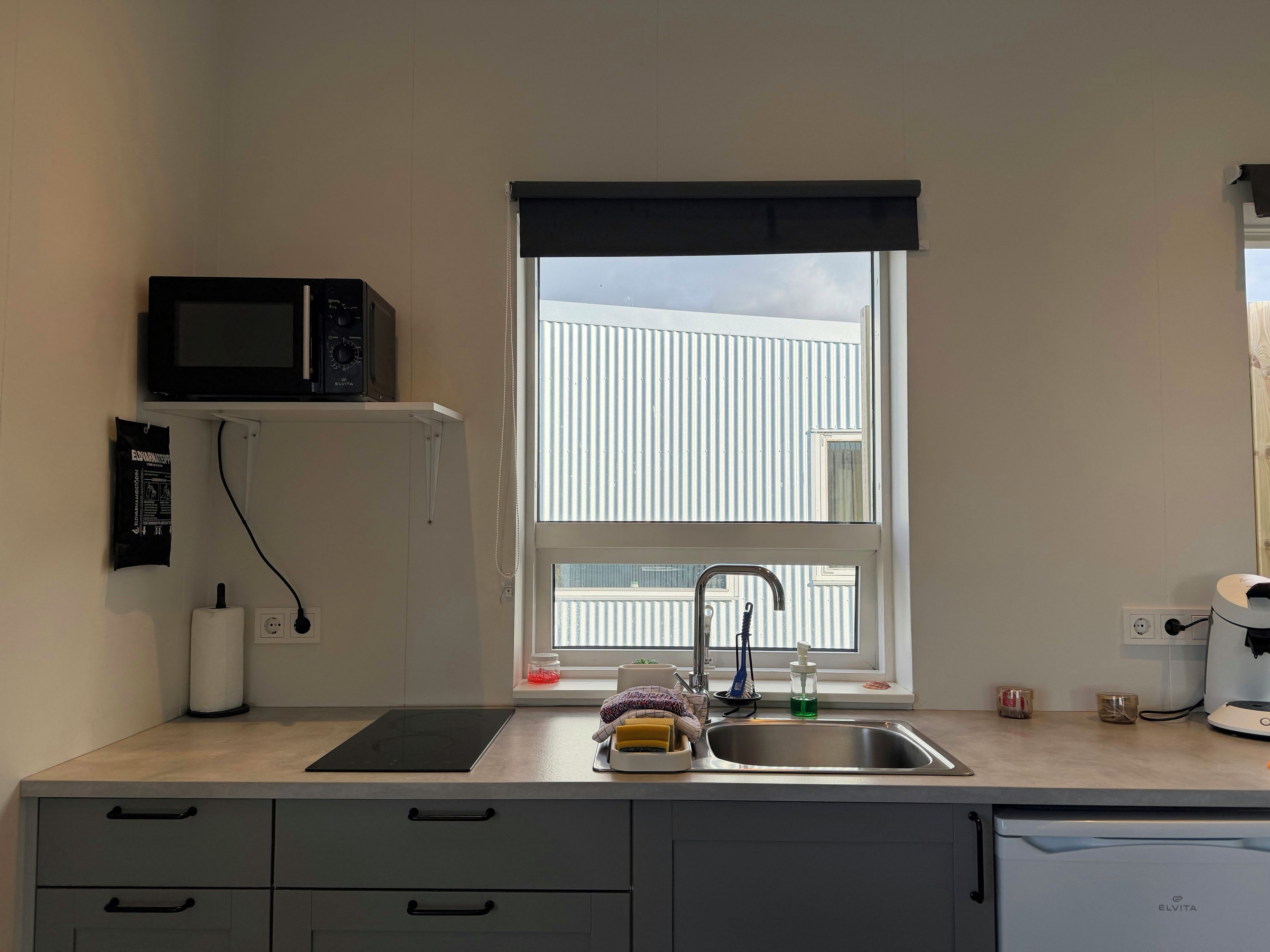 A kitchen with a window, a microwave, a sink, and a dishwasher.