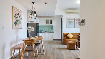 A modern living room with a dining area, a kitchen in the background, and a brown leather sofa.