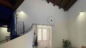 A cozy living room with a curved wooden ceiling, a staircase, a clock, and a window with curtains. - House with terrace near the Beach - Eden Holiday Home (Termini Imerese)