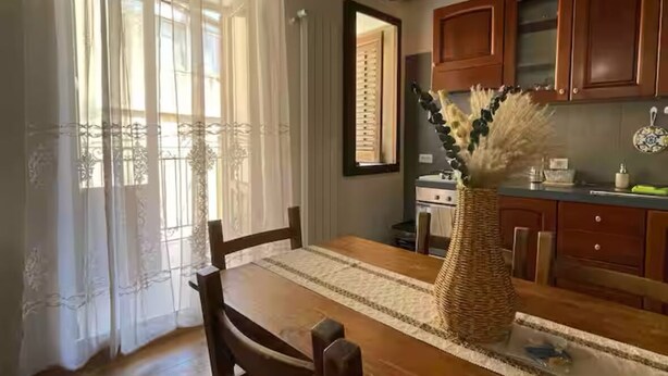 A dining area with a wooden table, chairs, and a vase of dried flowers. - House with terrace near the Beach - Eden Holiday Home (Termini Imerese)