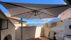 A compact balcony with a white umbrella, a small table, and a sink. - House with terrace near the Beach - Eden Holiday Home (Termini Imerese)