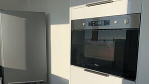 Moderni keittiö, jossa on sisäänrakennettu uuni ja jääkaappi.