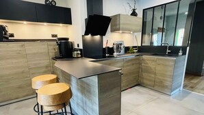 A modern kitchen with a central island, wooden cabinets, and two stools. - Crémieu, calm and relaxation, 2 steps from the center. (Crémieu)