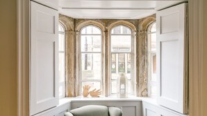 A room with a bay window, a chair, and a view of a street. - Lily Pad - 2-bed apartment with river views (Stamford)