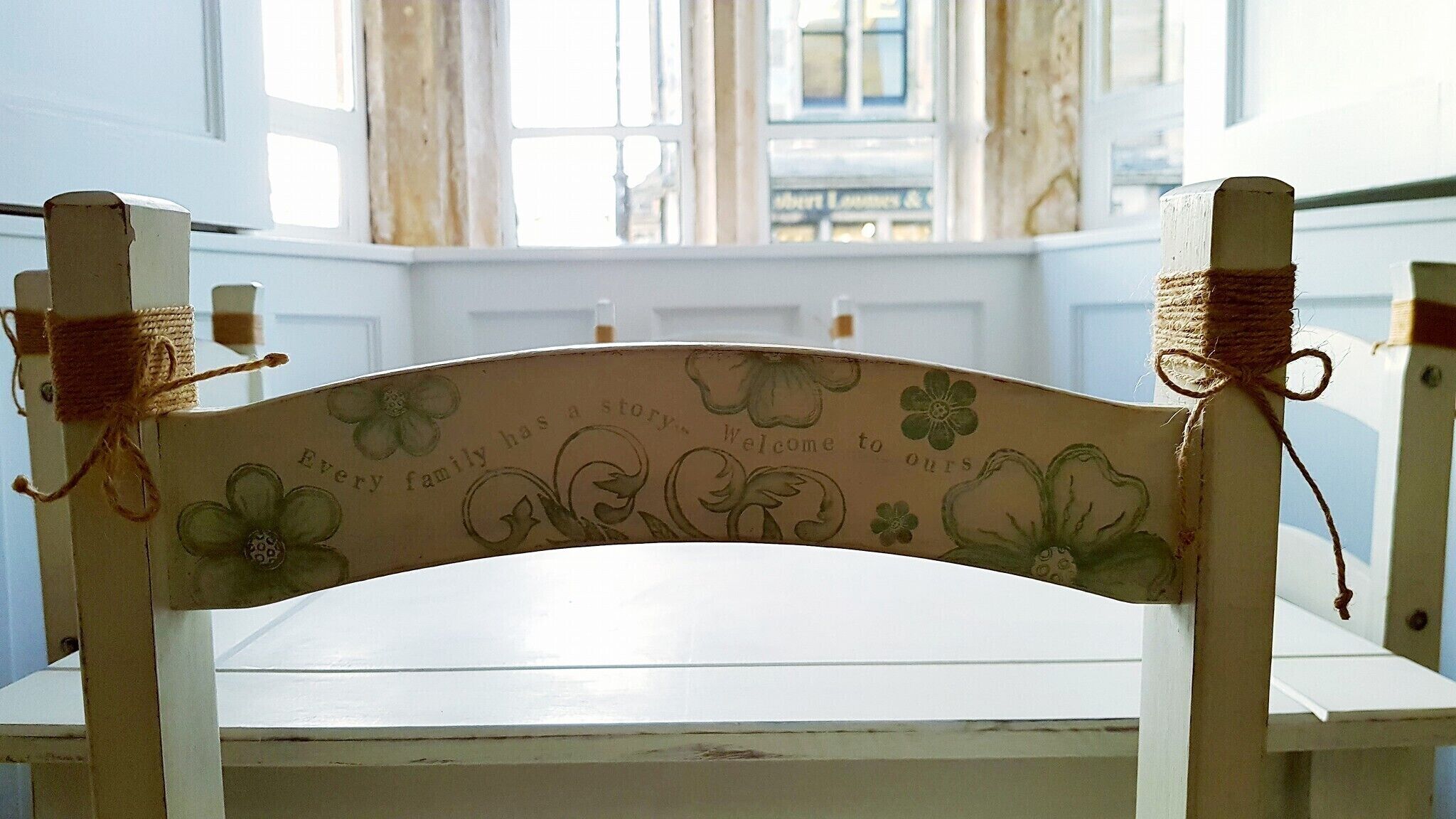 Een witte houten stoel met bloemenborduurwerk en een gebogen rugleuning.