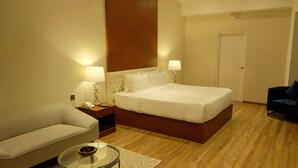 A hotel room with a bed, a nightstand, a lamp, a sofa, a coffee table, and a door. - Villa Isabel Hotel (Sorsogon City)