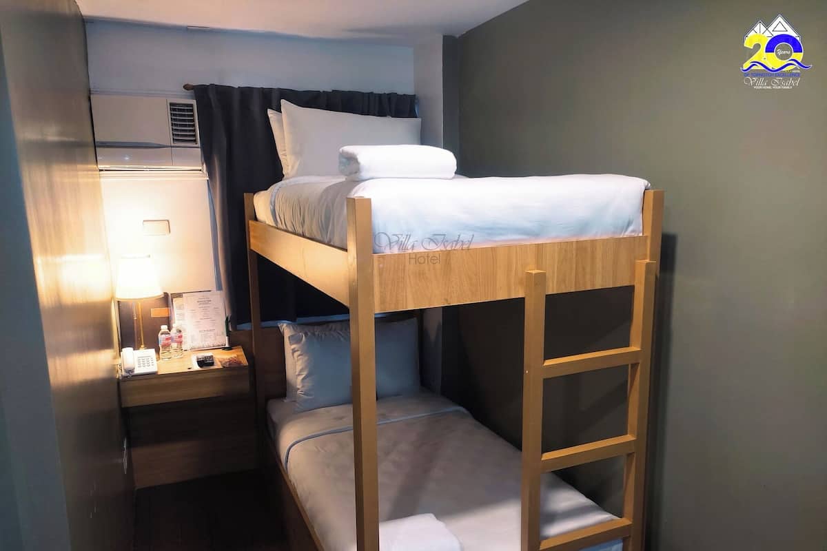 Une chambre avec un lit superposé, une échelle en bois, une table de chevet avec une lampe, un téléphone et un menu.