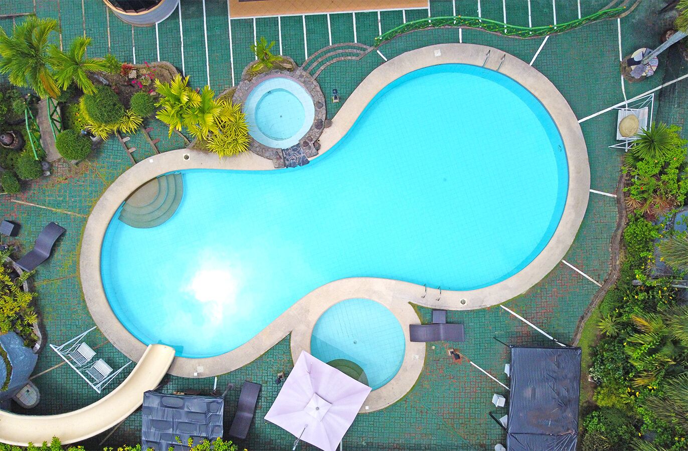 Una piscina al aire libre, sombrillas, sillones reclinables de piscina