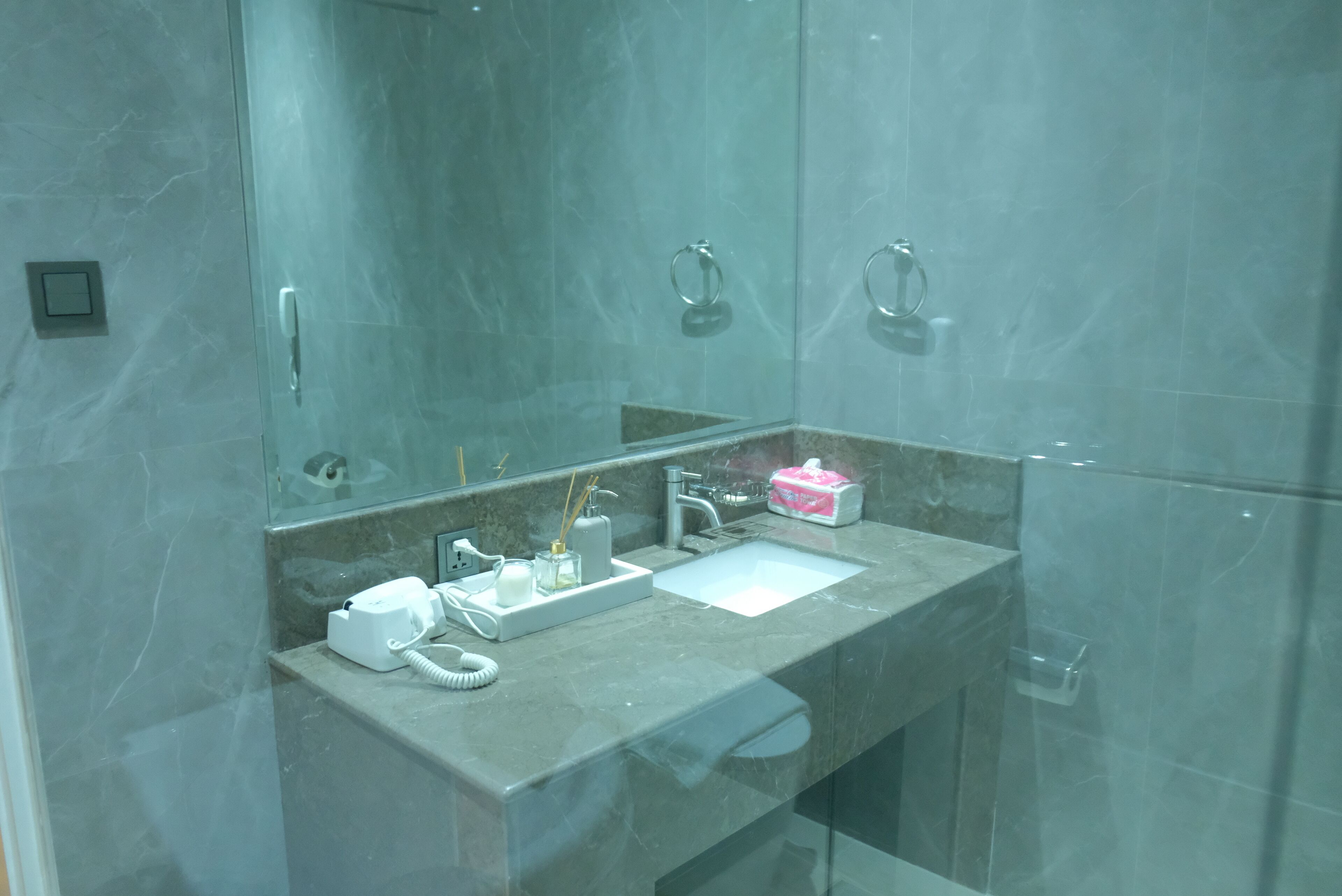 Un baño moderno con lavamanos de mármol, cabina de ducha con mampara de vidrio y un espejo.