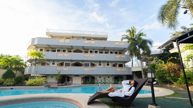 A person relaxing by a pool with a building in the background. - Villa Isabel Hotel (Sorsogon City)