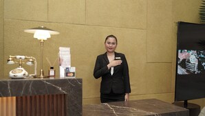 A reception area with a marble counter, a lamp, a name tag, and a television screen. - Villa Isabel Hotel (Sorsogon City)