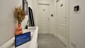 A reception desk with a welcome sign for Studio Donatello, a framed picture, and a vase with dried flowers. - Studio Donatello Flat (Milano)