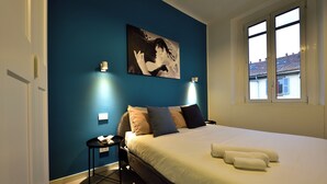 A bedroom with a bed, pillows, a bedside table, and a wall-mounted artwork. - Studio Donatello Flat (Milano)