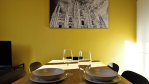 A dining table with two plates, two wine glasses, and a black chair. - Studio Donatello Flat (Milano)