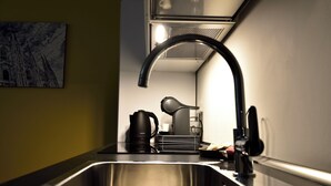 A modern kitchen with a stainless steel sink, a coffee maker, and a kettle. - Studio Donatello Flat (Milano)