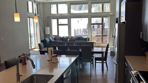 Een moderne keuken met een centraal eiland, roestvrijstalen apparatuur en grote ramen met uitzicht op een skipiste.