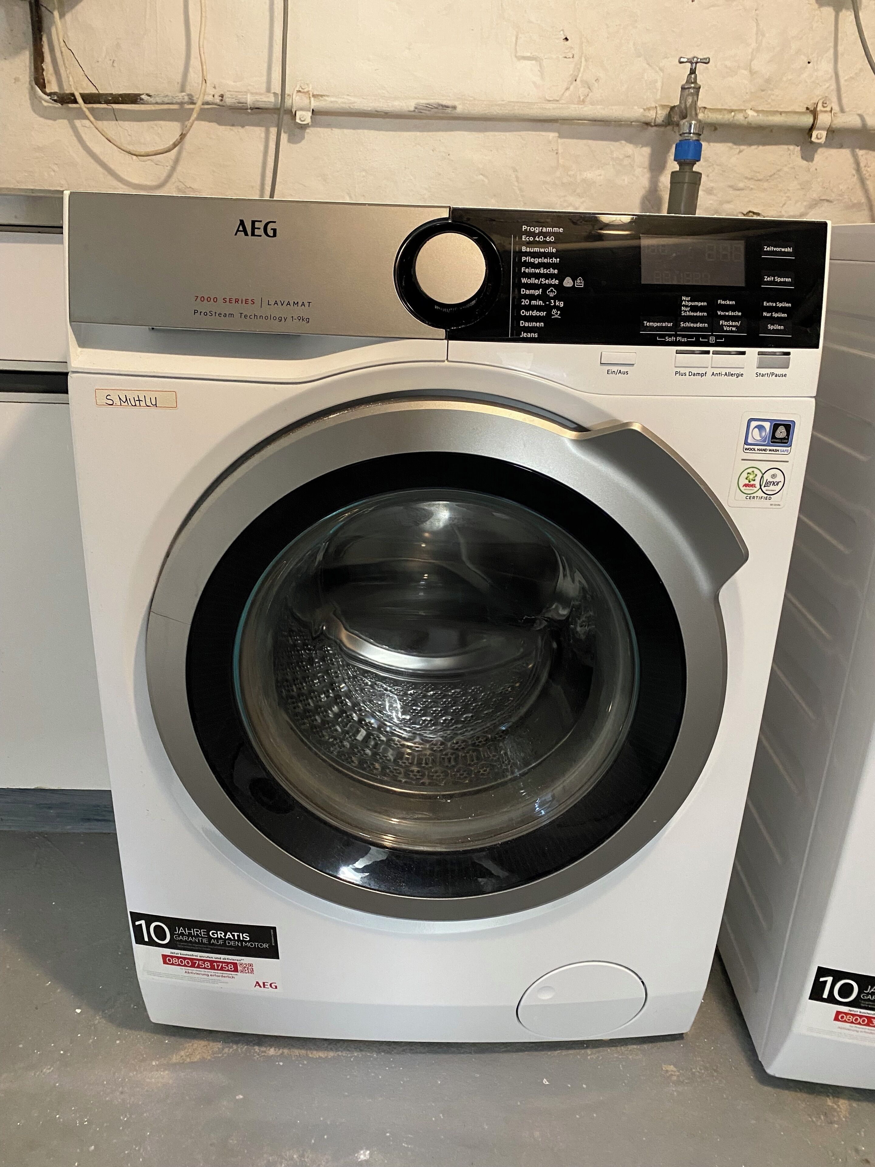 A front-loading AEG washing machine with a digital display, a 10-year motor guarantee, and a front-loading door.