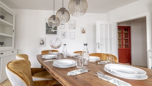 A dining area with a wooden table set for four, surrounded by upholstered chairs. There are hanging pendant lights above the table. - Gemütliches wohnen in idealer Lage, nahe Dortmund! (Holzwickede)
