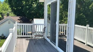 A covered deck with a railing, a table, and two chairs. - Stunning Lake Views with Balcony - with lake access (Allegan)