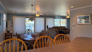 A dining area with a table, chairs, ceiling fan, and large windows. - Stunning Lake Views with Balcony - with lake access (Allegan)