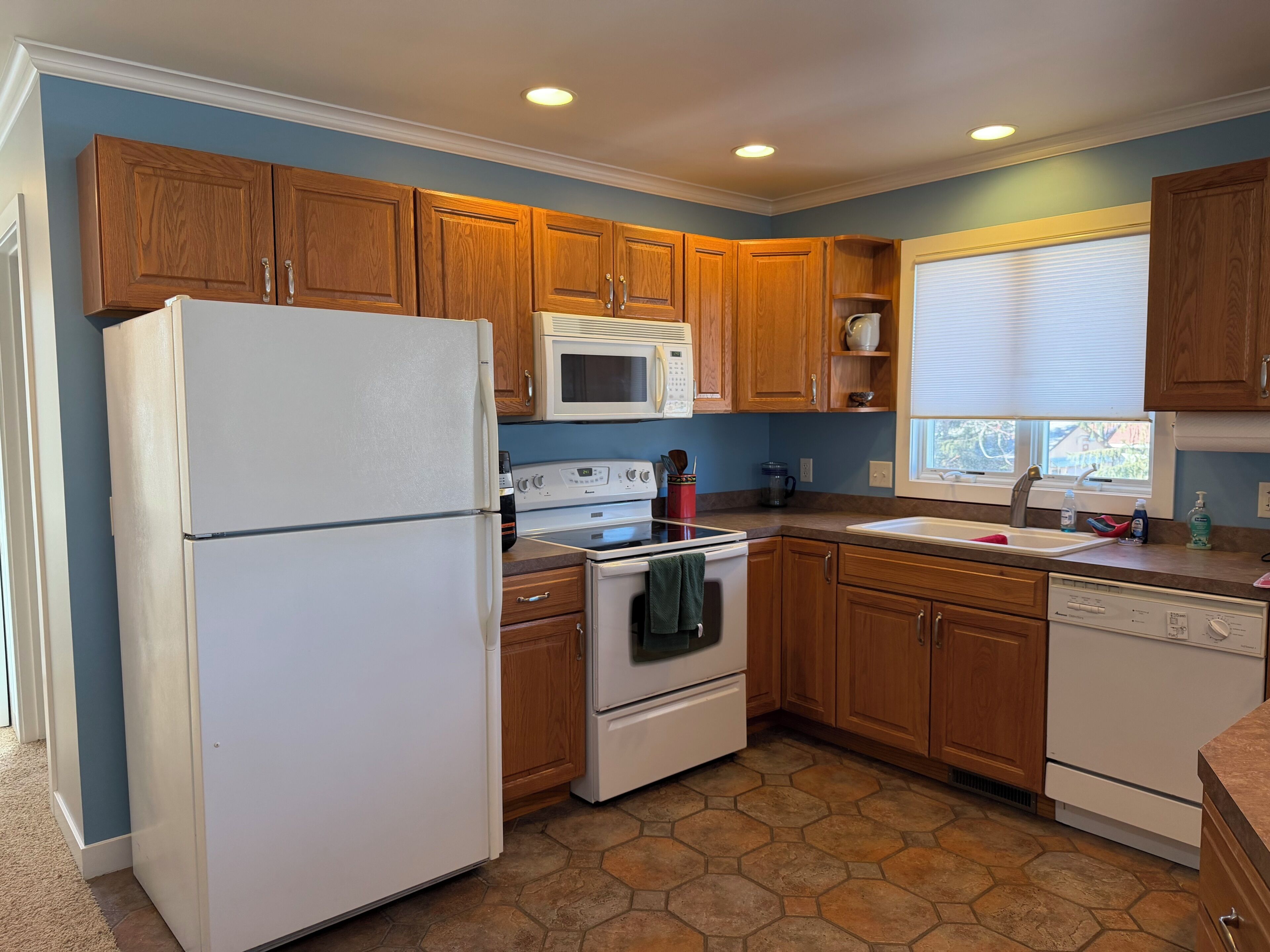 A kitchen with wooden cabinets, a white refrigerator, a microwave, an oven, and a dishwasher.