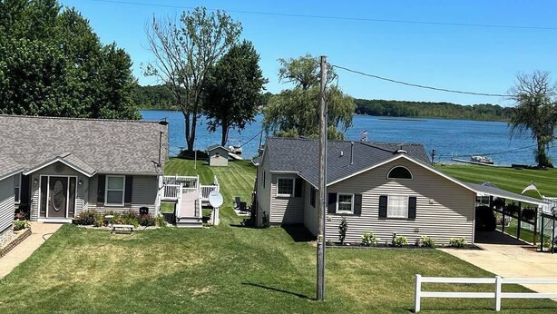 A lakeside property with two houses, a dock, and a grassy lawn. - Stunning Lake Views with Balcony - with lake access (Allegan)