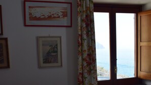 Un salon avec un canapé, une fenêtre donnant sur un beau paysage et des tableaux encadrés accrochés au mur.