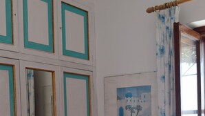 Une pièce comprenant un lit, une chaise, une armoire, un tableau et une fenêtre avec des rideaux.