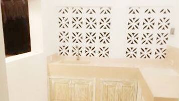 Une pièce aux murs blancs, avec un banc intégré le long du mur et un panneau mural décoré d’un motif.