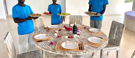 A round table set for a meal with plates, glasses, and a bottle of champagne.