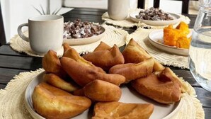 Una mesa de comedor con un plato de pasteles, una taza y un vaso de agua.