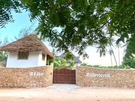 A rustic house with a thatched roof, surrounded by a gravel wall.
