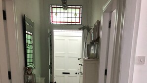 Un pasillo estrecho con suelo de madera, puertas blancas y un escalón pequeño que lleva a una puerta blanca al final.