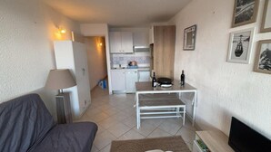 Um espaço de estar compacto com cozinha compacta, mesa de jantar e sofá.