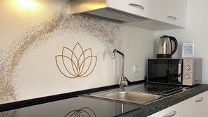 Una cocina moderna con un lavamanos de acero inoxidable, un microondas y una estufa a gas.