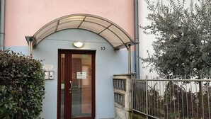 Un edificio de fachada rosa, entrada numerada y valla metálica.