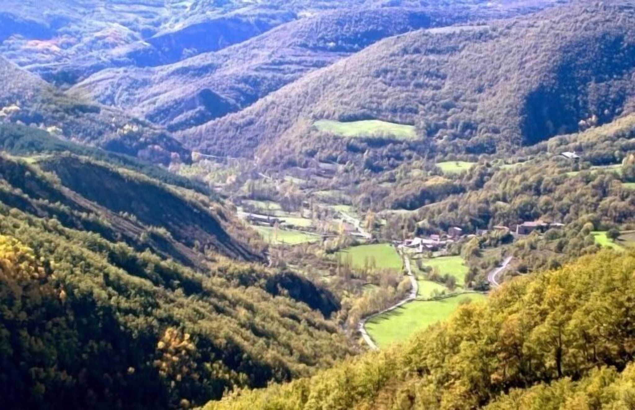 Una valle con un piccolo insediamento circondato da colline.