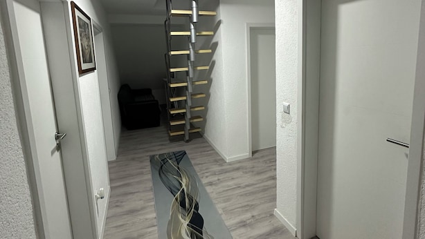 A hallway with a staircase, white walls, and a wooden floor. - Vacation apartments near Legoland-Günzburg (Günzburg)
