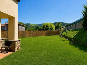 A well-maintained lawn with a stone bench and a wooden fence.