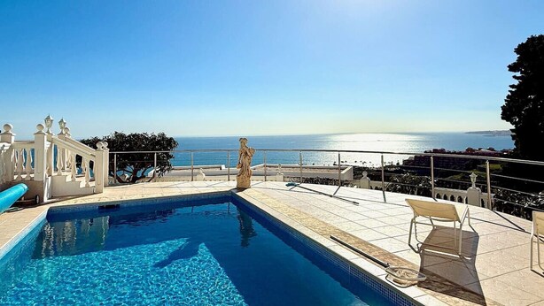Une piscine à l’eau d’un bleu cristallin, une statue et une vue sur l’océan.