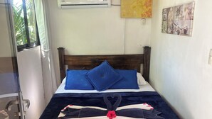 Un dormitorio con cama de madera, colcha azul y un arreglo decorativo con forma de corazón sobre la cama.